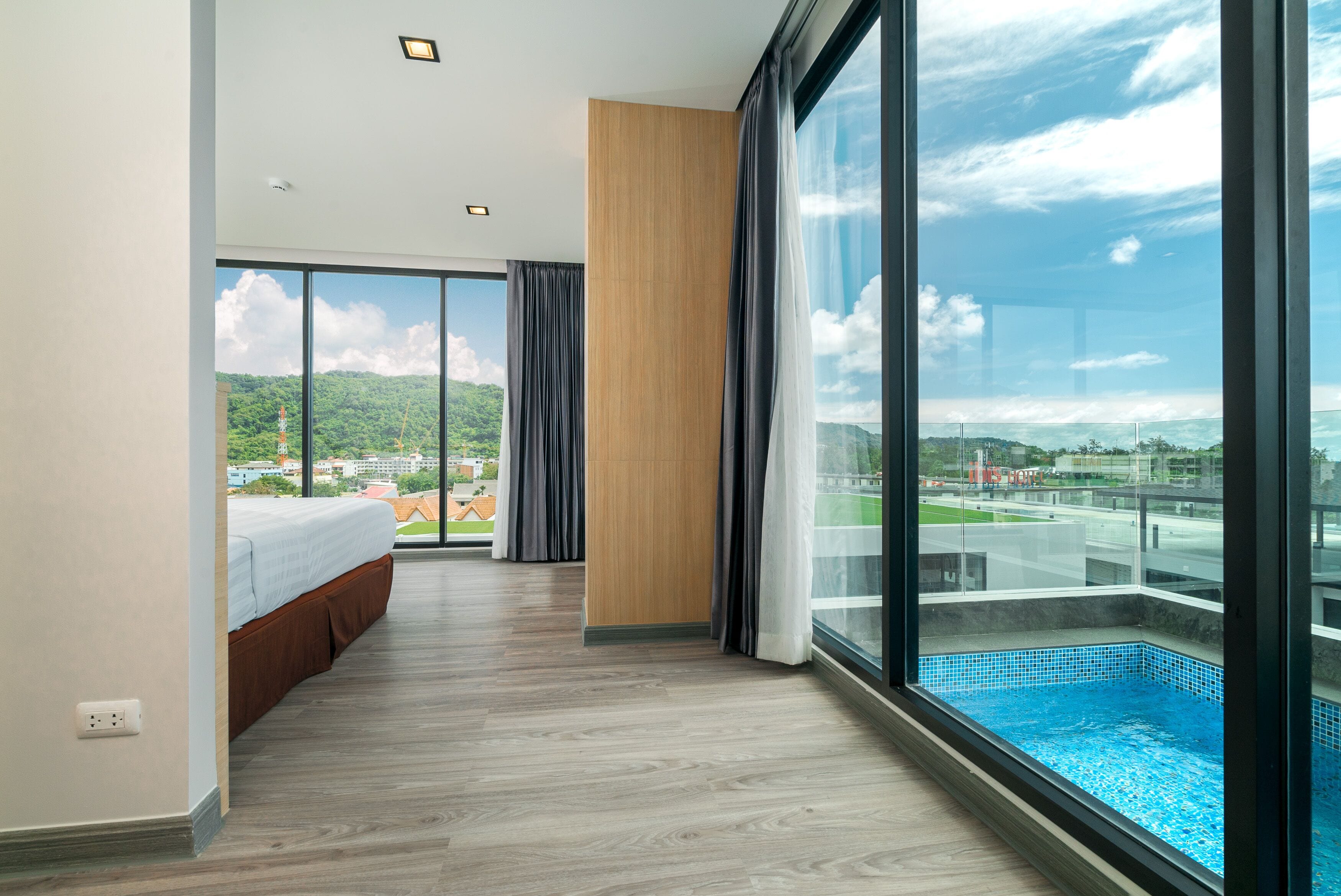 Quarto de hotel moderno com varanda ampla, vista para o mar e parede de destaque em madeira.