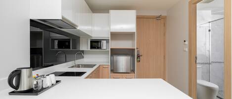 Eine moderne Küche mit weißen Schränken, einem Edelstahl-Kühlschrank und einer Kaffeestation.