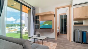 Una sala de estar moderna con un televisor grande, un sofá, una mesa de centro y equipaje.