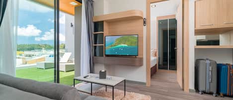 Una sala de estar moderna con un televisor grande, un sofá, una mesa de centro y equipaje.