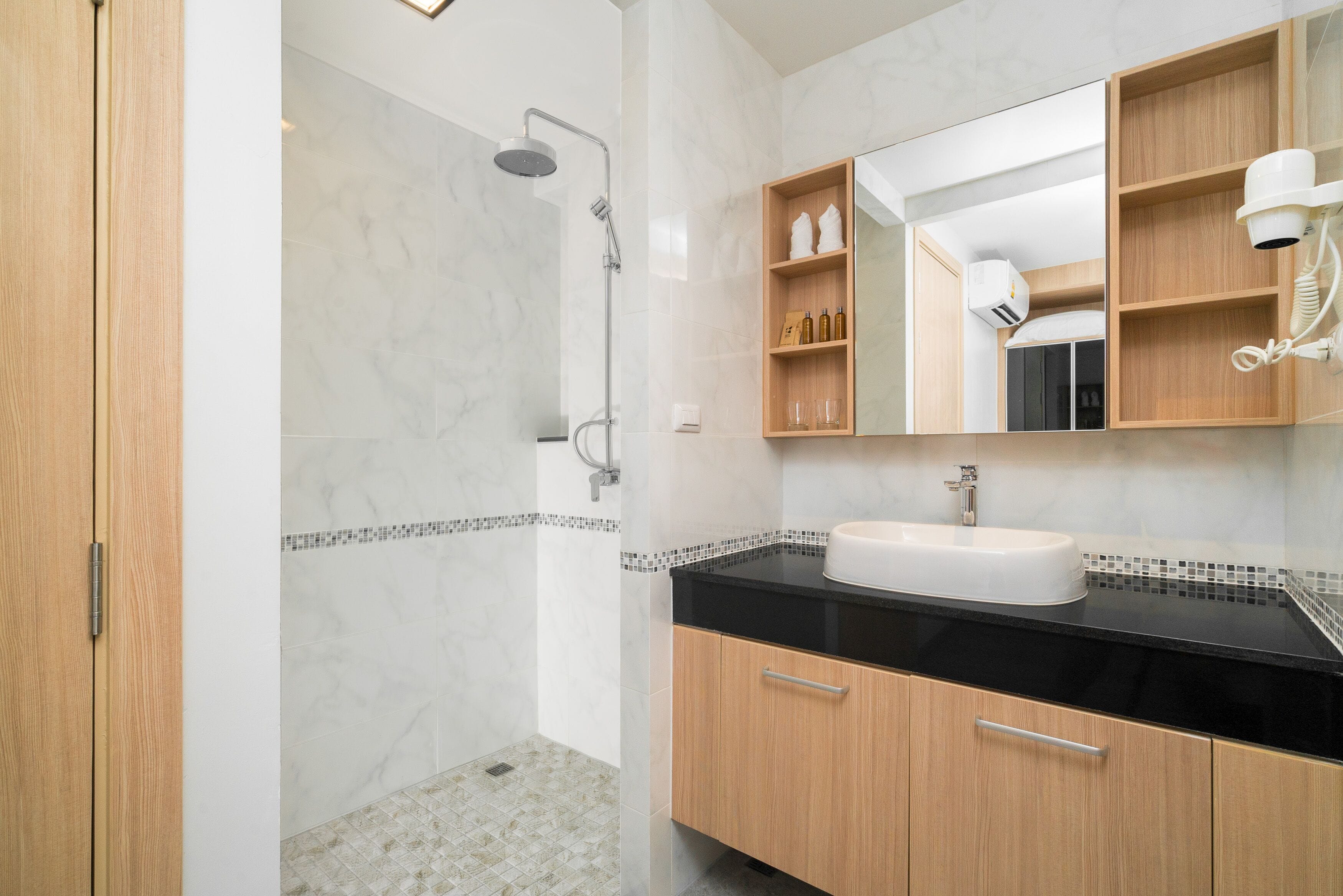A modern bathroom with a shower, vanity, and built-in shelves.