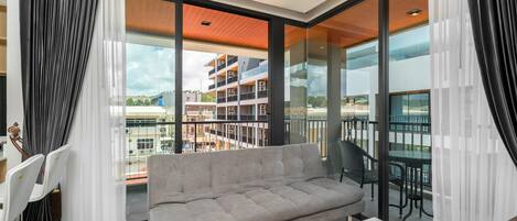 A modern living room with a grey sofa, a coffee table, and a view of a balcony with outdoor furniture.
