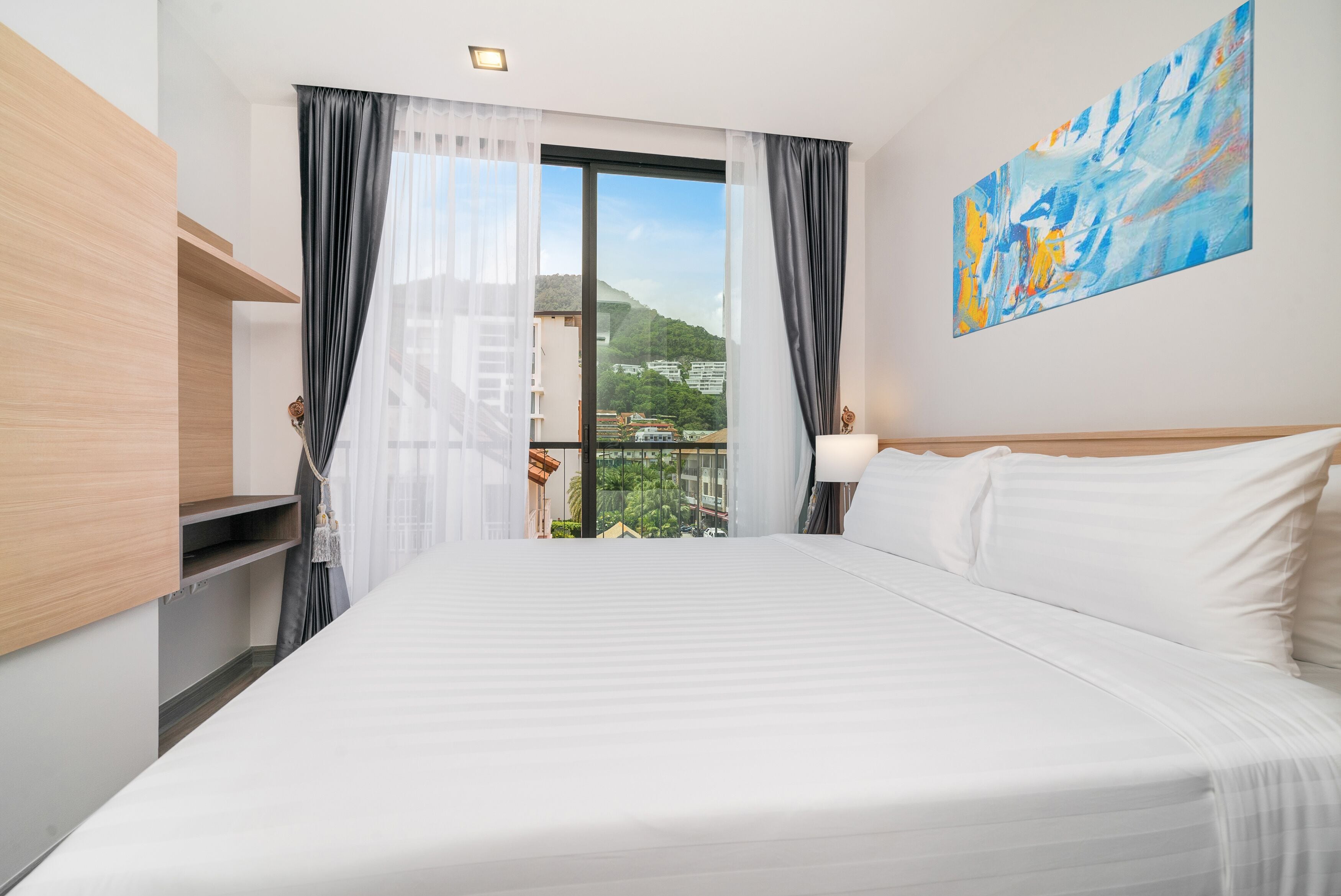 Una habitación de hotel con una cama grande, vistas de la ciudad y un cuadro en la pared.