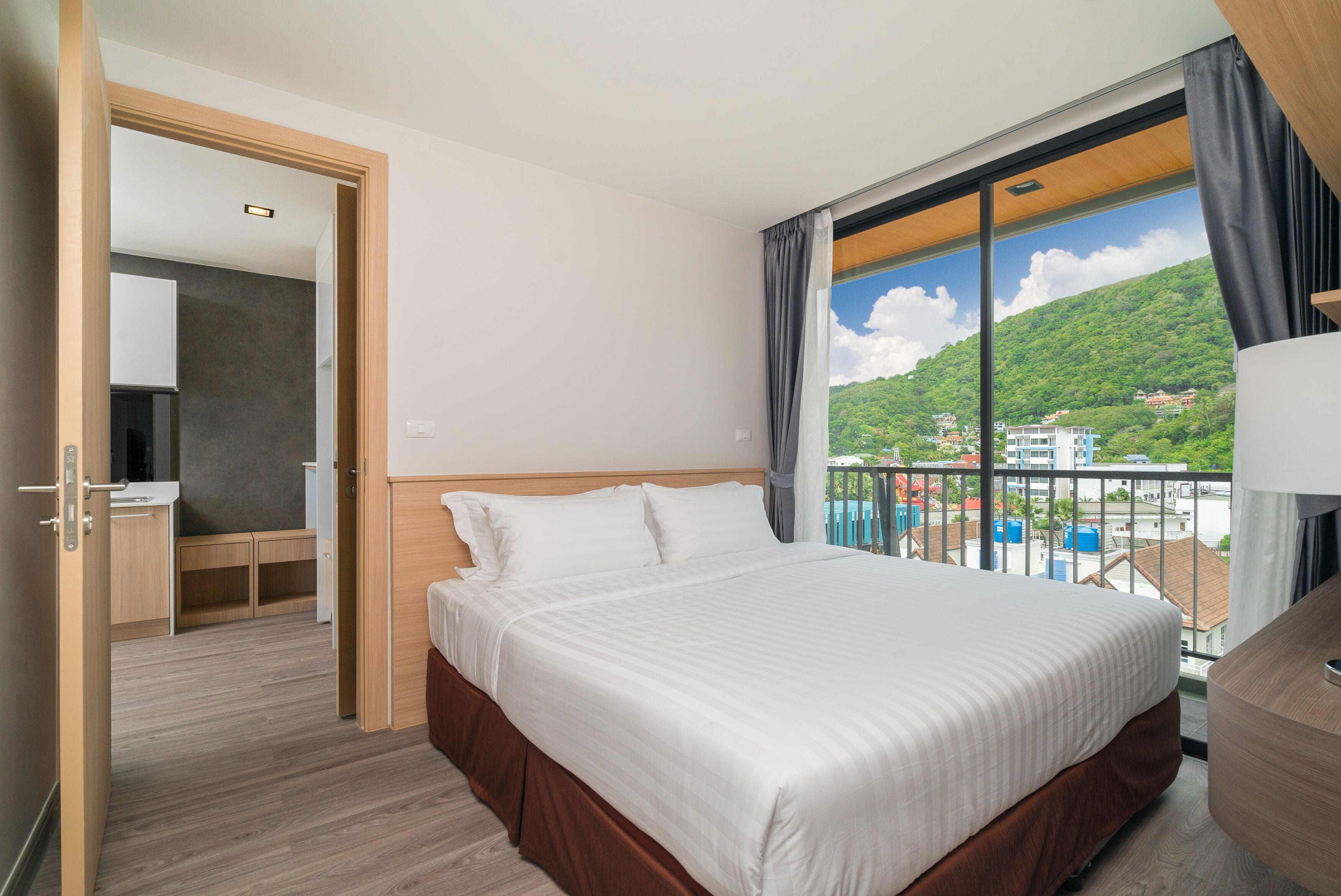Habitación de hotel con una cama grande, un escritorio y vistas a un paisaje montañoso.