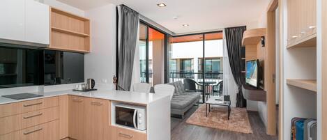 A modern kitchen with built-in appliances, a dining area with a table and chairs, a sofa, and a large window with curtains.