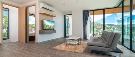 A modern living room with a sofa, a coffee table, and a flat-screen TV mounted on the wall.
