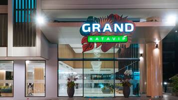 Una entrada de hotel moderna con un llamativo letrero que dice 'GRAND' y 'KATAVIP' debajo.