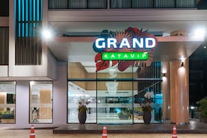 Una entrada de hotel moderna con un llamativo letrero que dice 'GRAND' y 'KATAVIP' debajo.