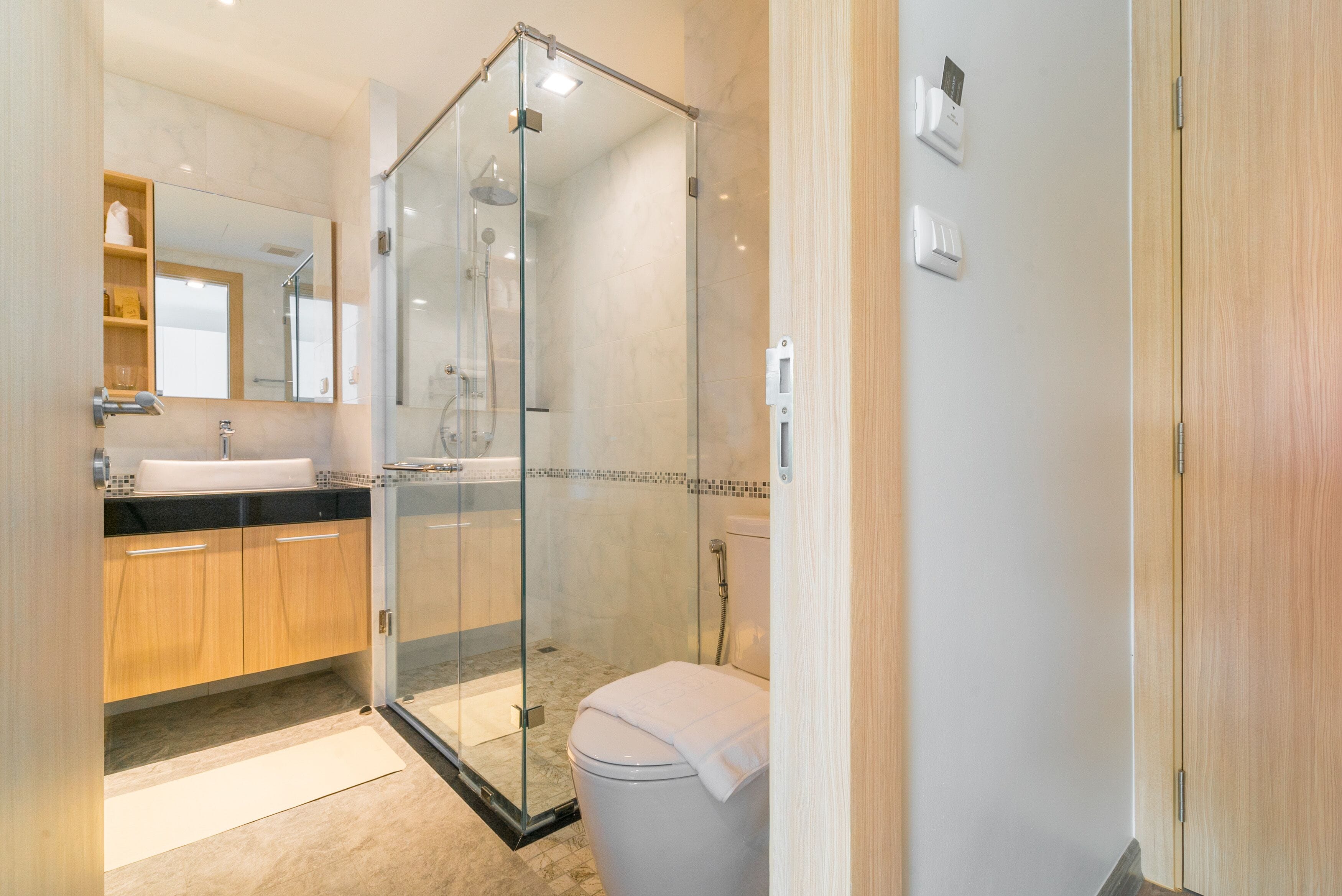 A modern bathroom with a glass-enclosed shower, a sink, and a toilet.