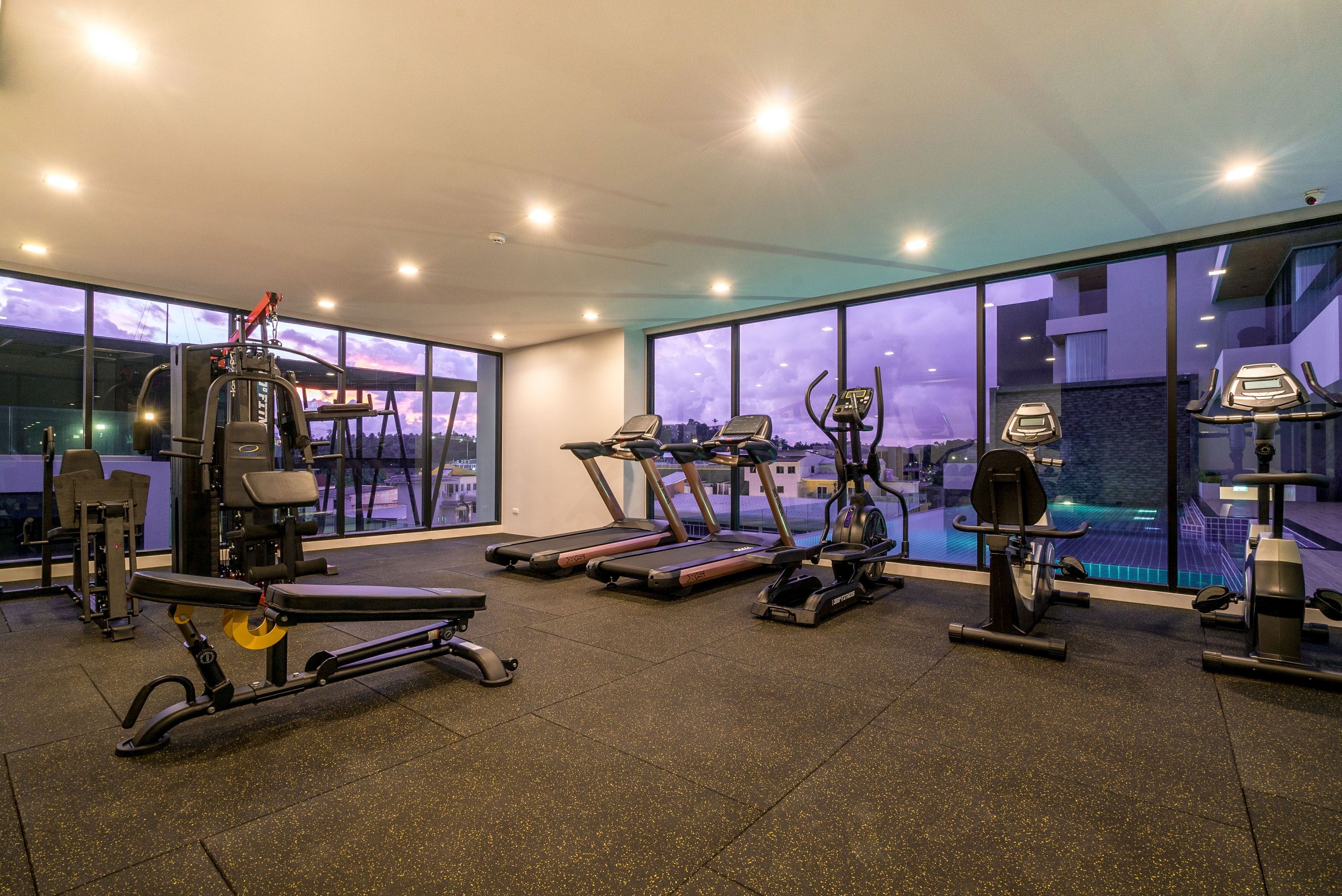 Un gimnasio moderno con cintas de correr, elípticas y equipamiento de levantamiento de pesas.