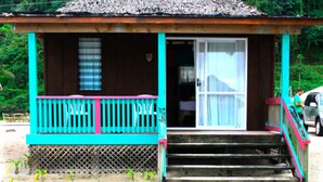 Una casa de madera con un porche, una puerta y escalones que llevan a la entrada.