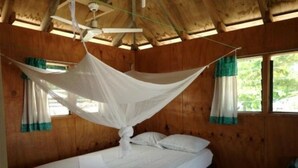 Una cama con dosel, paredes de madera y ventanas con cortinas.