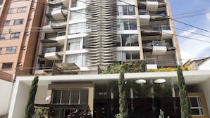 Un immeuble à plusieurs étages doté de balcons, d’une devanture de magasin et d’un parking.