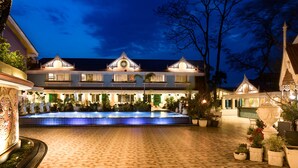 A courtyard with a tiled pool, ornate architecture, and potted plants. - MAYFAIR Himalayan Spa Resort (Kalimpong)