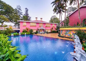 A large, pink building with a swimming pool in front.