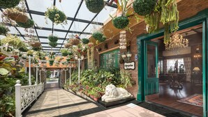 A corridor with hanging plants, a reception desk, and a statue of a lion. - MAYFAIR Himalayan Spa Resort (Kalimpong)