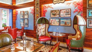 A restaurant with wooden paneling, red and green upholstered chairs, and framed pictures on the walls. - MAYFAIR Himalayan Spa Resort (Kalimpong)