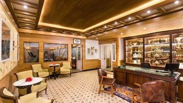 A hotel lobby with wooden paneling, a reception desk, and a display of local crafts.