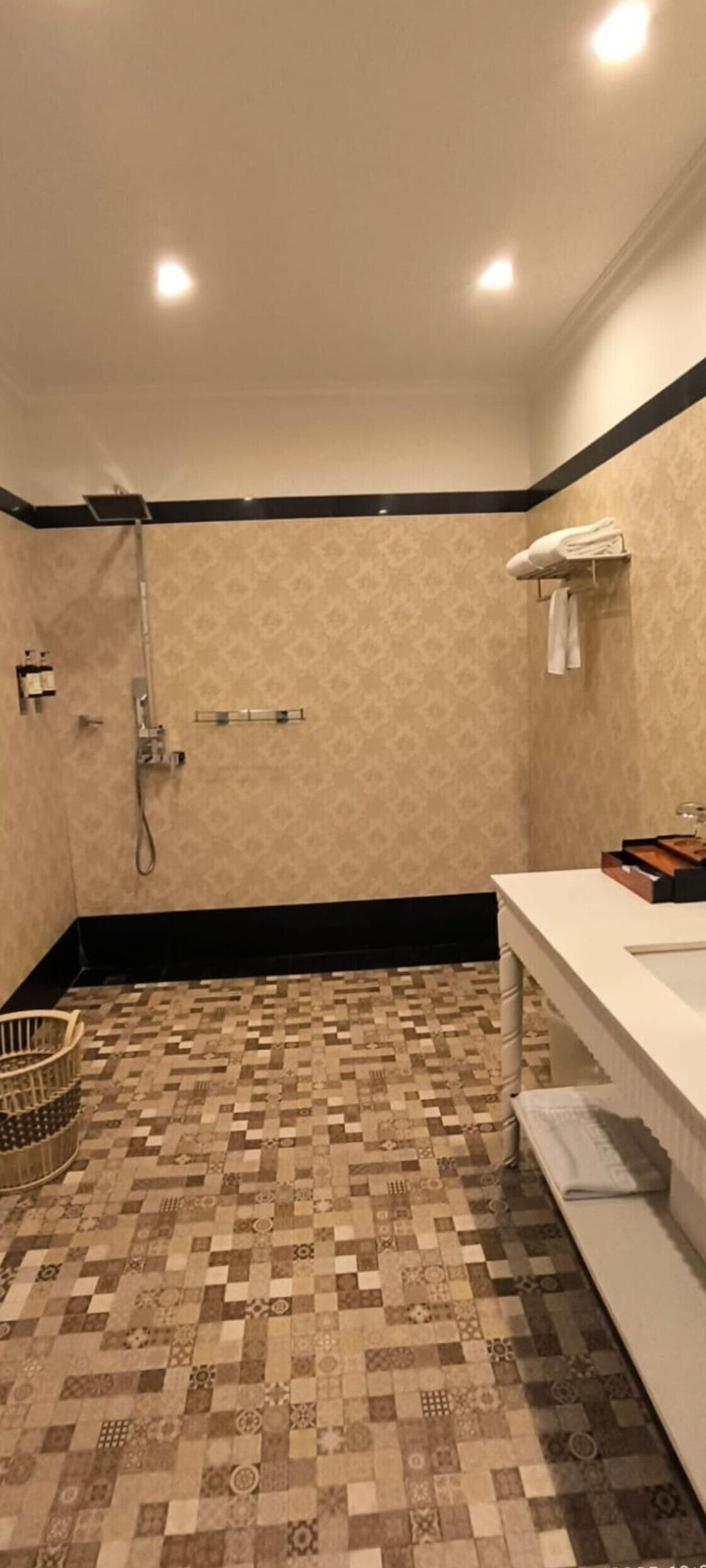 Um banheiro com azulejos estampados, pia branca e porta-toalhas.