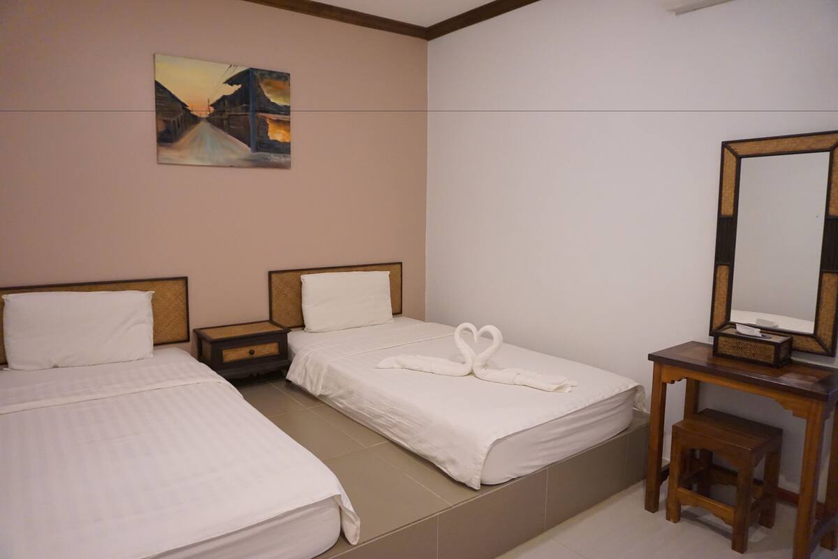 Une chambre d’hôtel avec deux lits, un bureau, une chaise, un miroir et un tableau au mur.