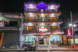 A multi-story hotel with balconies, a sign indicating it is a hotel, and a motorcycle parked in front. - Hotel Middle East (Pokhara)