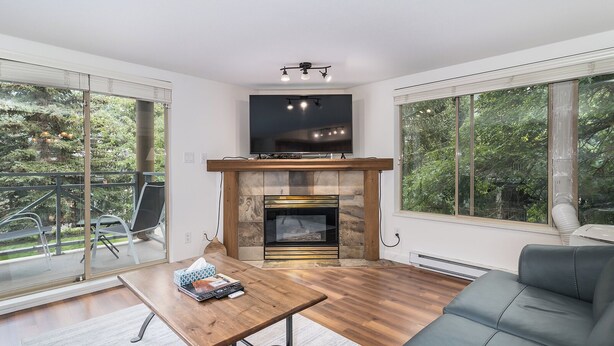 Una sala de estar moderna con chimenea, ventanas amplias y un balcón.