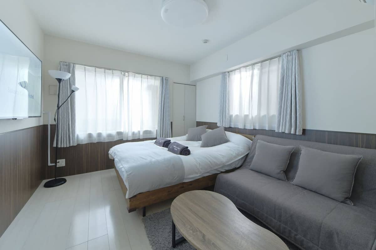 Una habitación de hotel moderna con cama, sofá, una mesita y televisor.