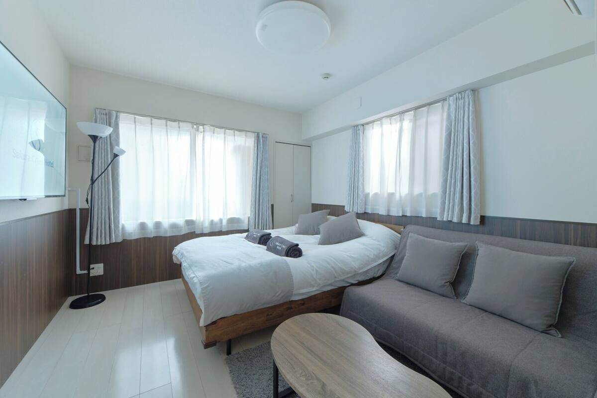 Ein modernes Hotelzimmer mit einem großen Bett, einer Couch, einem kleinen Tisch und einem Fernseher.