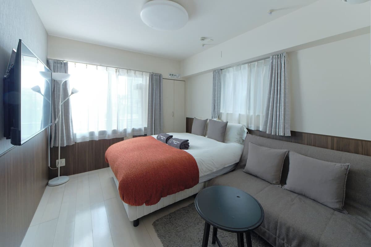 Ein modernes Hotelzimmer mit einem Bett, einer Couch, einem kleinen Tisch und einem Fernseher.