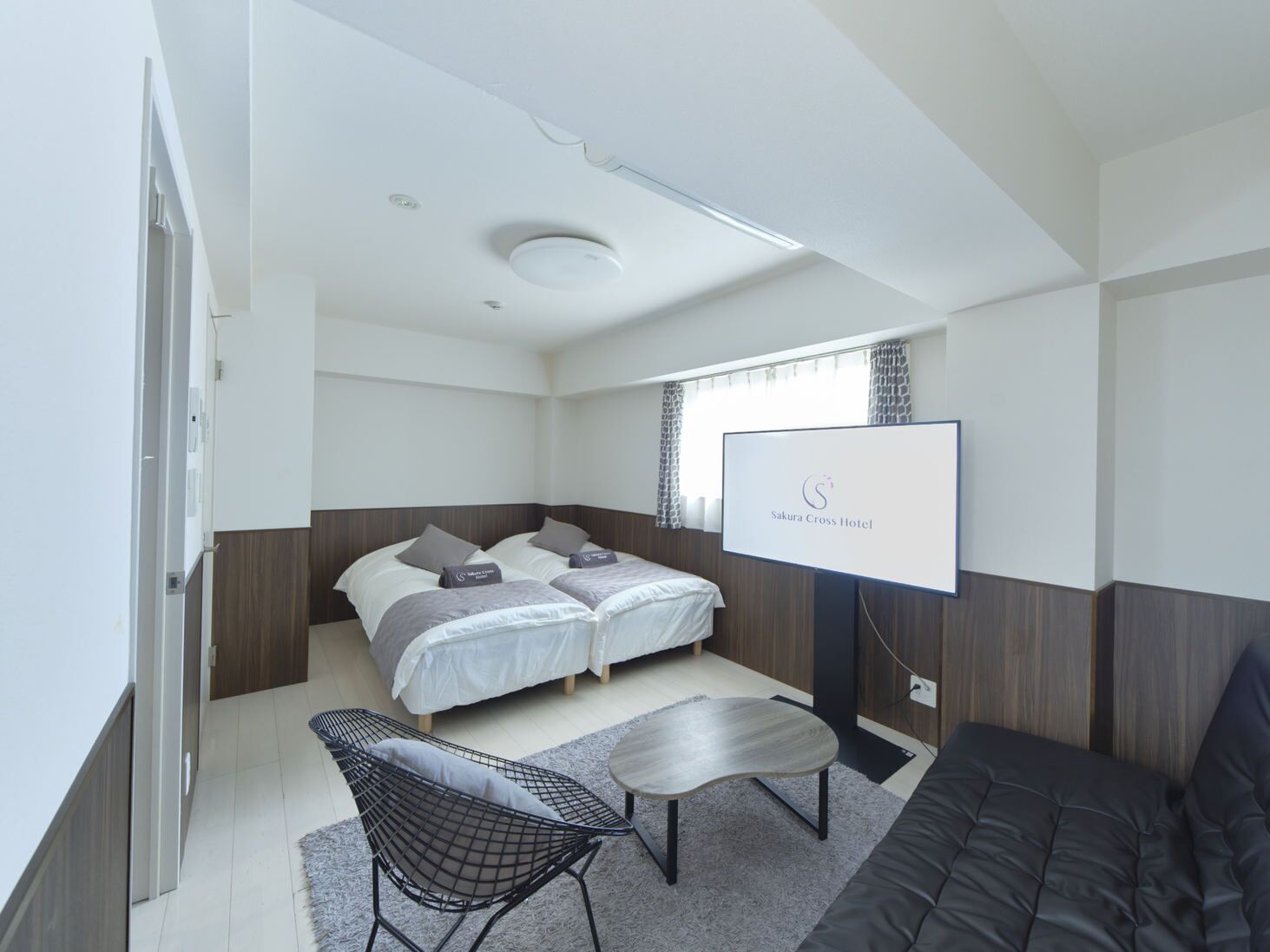 Una camera d'albergo moderna con un letto, una poltrona, una TV e un tavolino.