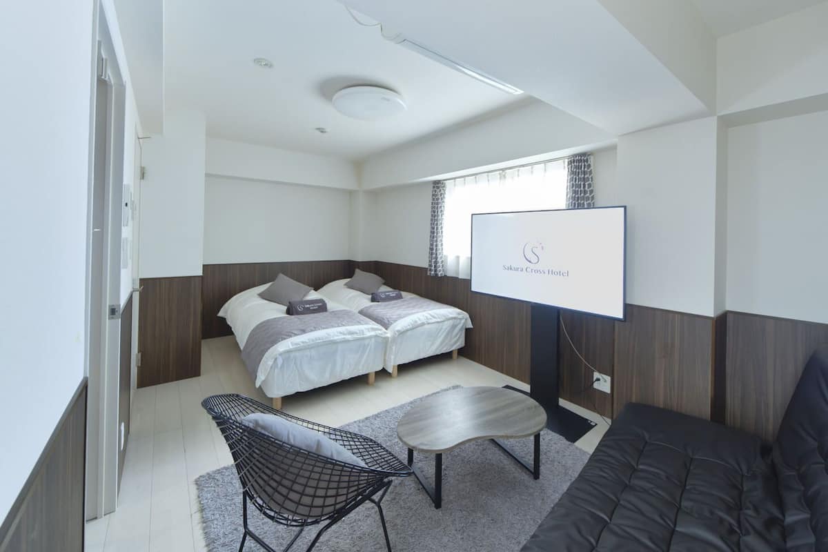Una habitación de hotel moderna con una cama, un sofá, un televisor y una mesita.