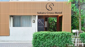 The exterior of Sakura Cross Hotel with a modern design, featuring a wooden facade and a signboard.