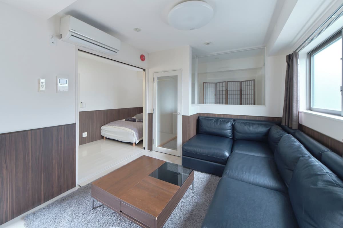 Ein modernes Hotelzimmer mit einer Couch, einem kleinen Tisch, einem Bett und einer Schiebetür zum Balkon.