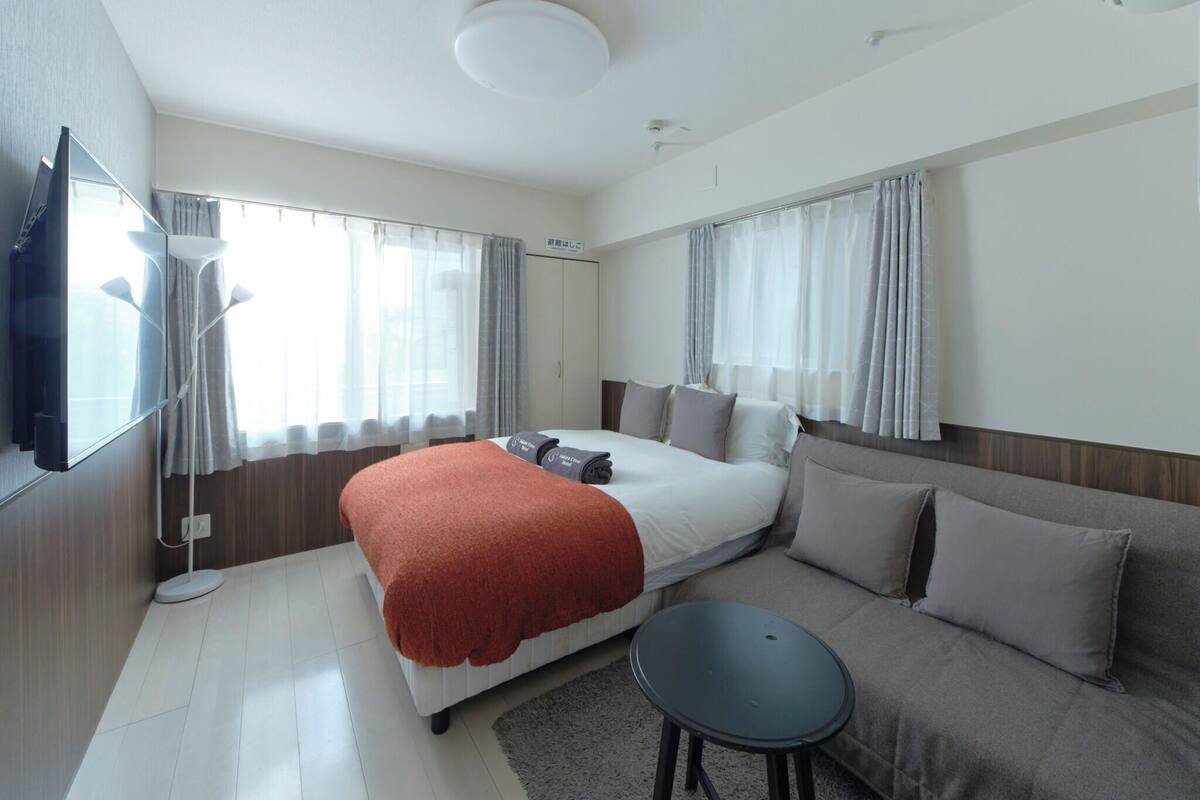 Ein modernes Hotelzimmer mit einem Bett, einer Couch, einem kleinen Tisch und einem Fernseher.