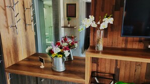 A wooden interior with a metal coffee pot, a vase with flowers, and a framed picture on the wall.