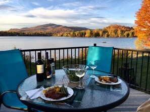 A table set with wine, glasses, and plates of food, overlooking a lake with autumn foliage and mountains in the background. - Lakefront Chalet Mont Tremblant - Spectacular view - WIFI (CITQ 294661) (Lac-Supérieur)