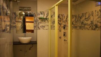 Une salle de bain avec un mur en marbre, un lavabo, un miroir et un espace douche.