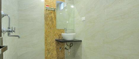 Un baño con pared de mármol, un lavamanos, un espejo y una ducha.