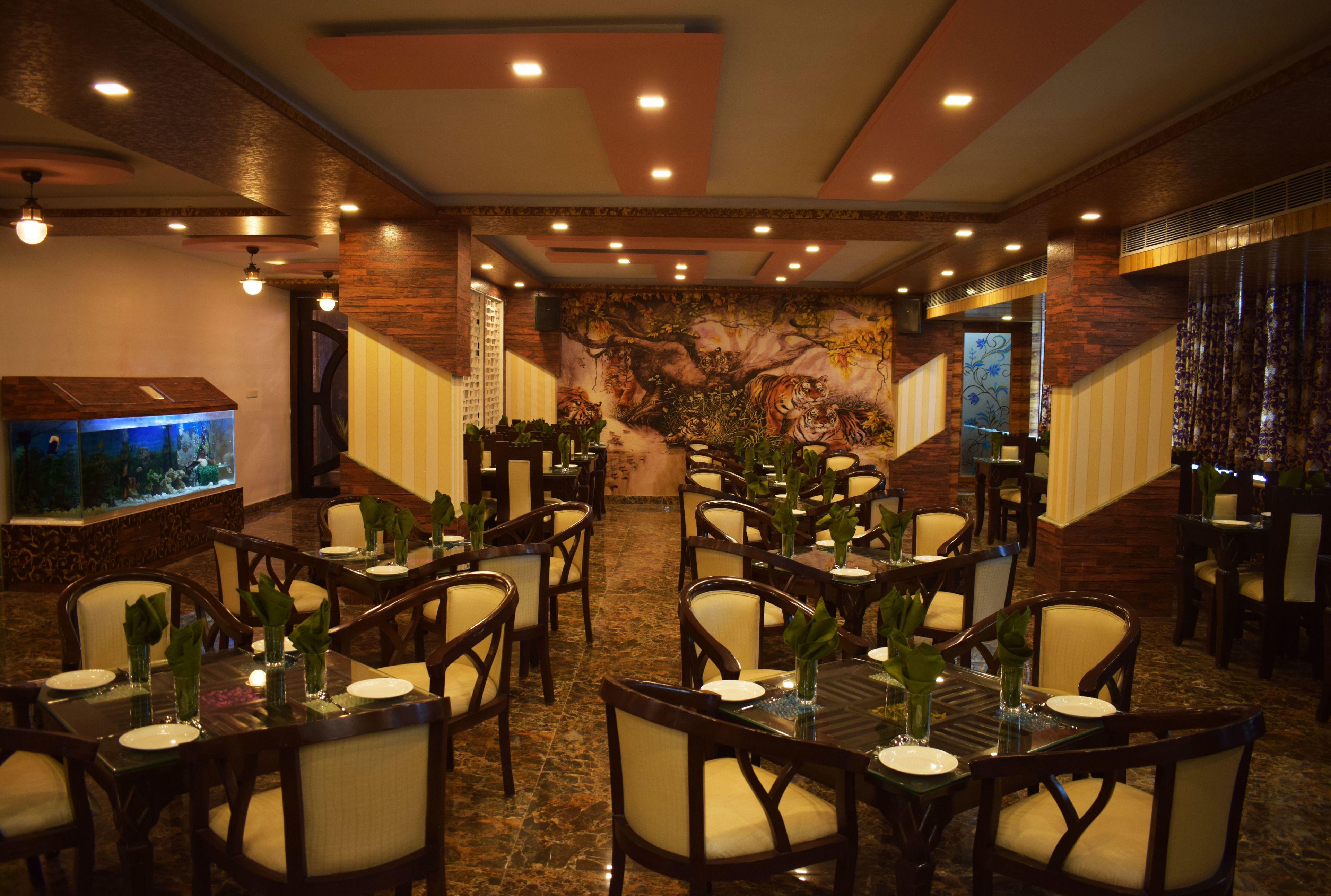 A restaurant with multiple tables and chairs, a large aquarium, and a mural on the wall.