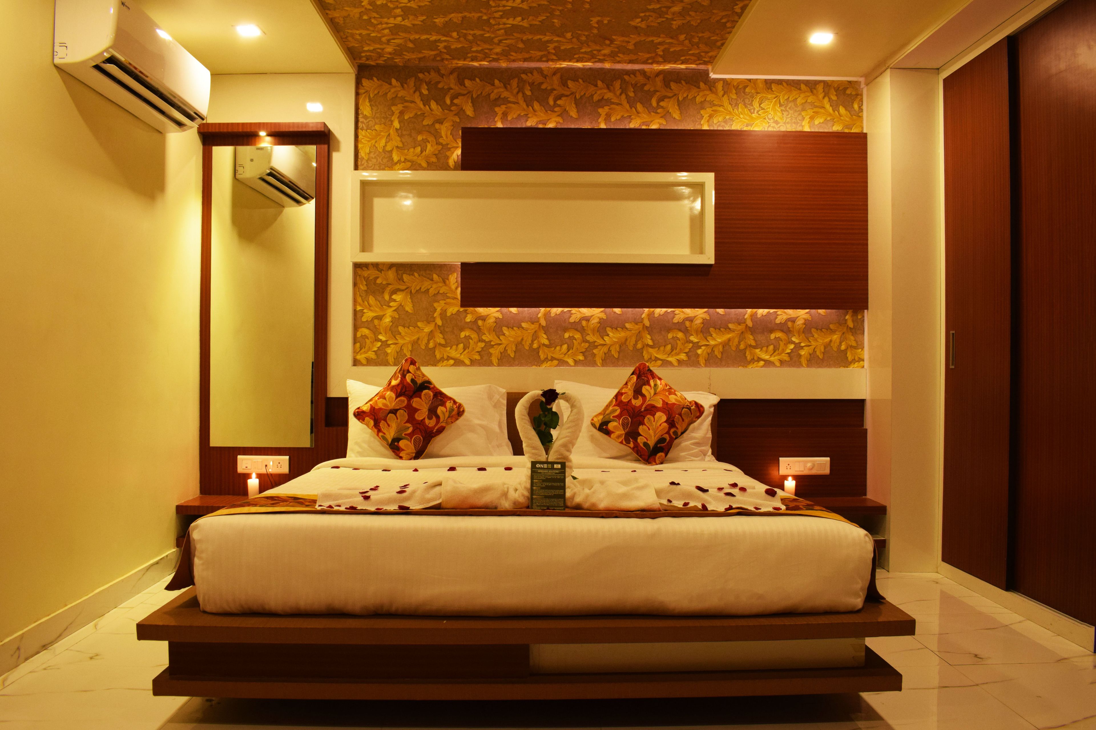 Quarto de hotel moderno com uma cama grande, ar condicionado instalado, um espelho e um detalhe decorativo na parede.