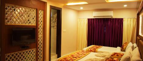 A hotel room with two beds, a TV, and an air conditioning unit.