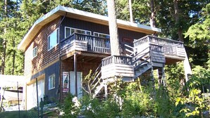 A wooden cabin with a balcony and a staircase. - Private waterfront cottage on Malaspina Strait with easy access to town/trails (Powell River)