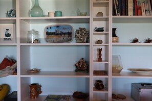 A bookshelf with various decorative items, including ceramics, figurines, and books. - Far View - Pets, Linen, Wi-Fi, Netflix, Free EV charger (Venus Bay)