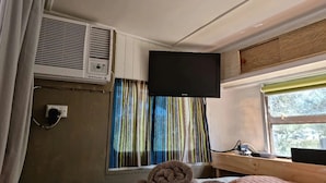A room with a bed, a window with curtains, an air conditioning unit, and a flat-screen TV mounted on the wall. - Far View - Pets,  Linen,  Wi-Fi, Netflix, Caravan, EV charger (Venus Bay)