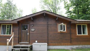 Eine Holzhütte mit Haustür, einer kleinen Veranda und einem Briefkasten.