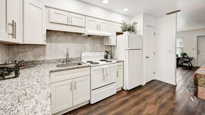 A modern kitchen with white cabinetry, a granite countertop, a built-in oven, and a refrigerator. - Sarasota Downtown Apartment!!! (Sarasota)