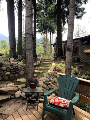 A wooden deck with a green chair and a table with a potted plant.