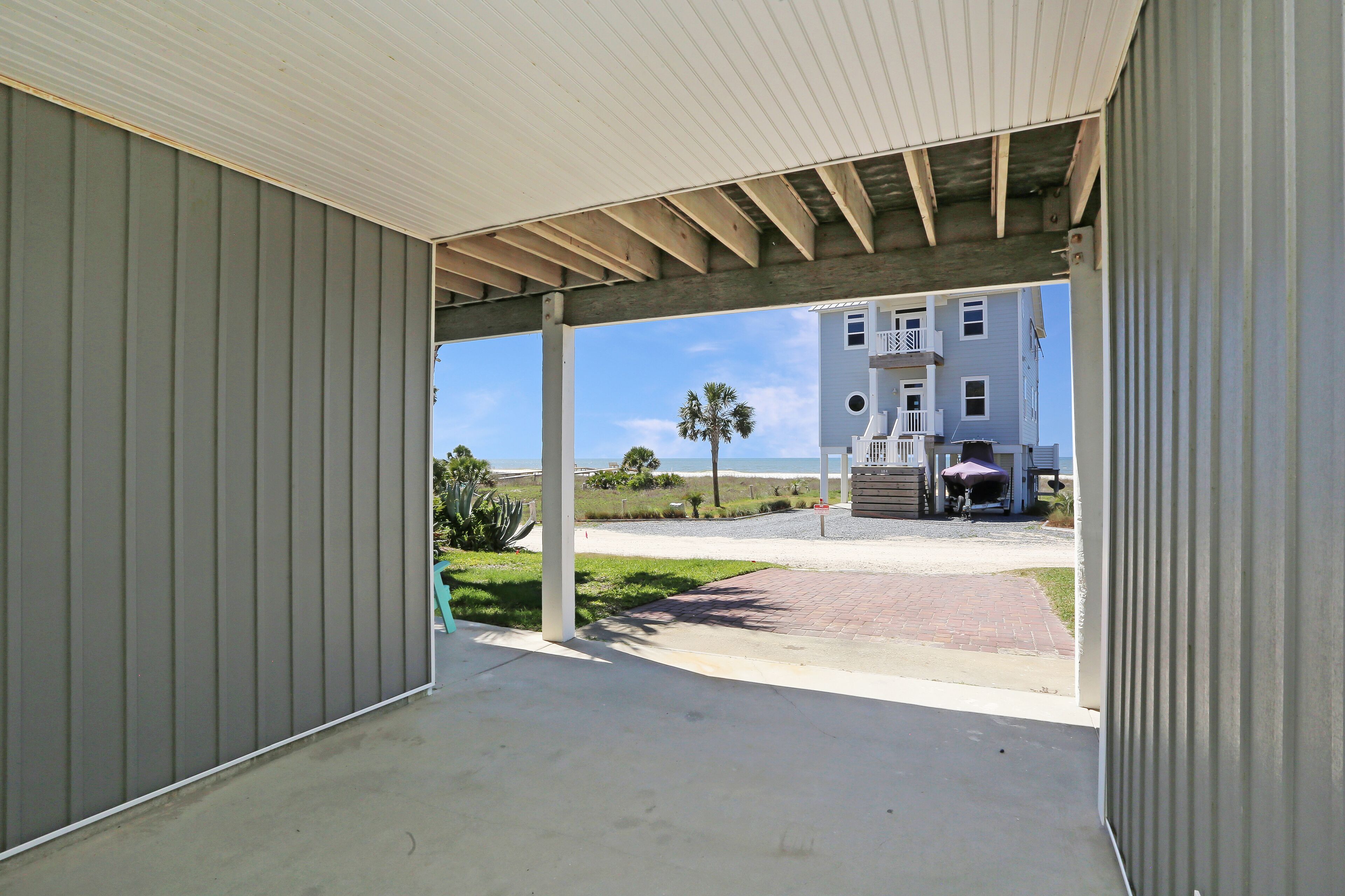 A covered outdoor area with a view of a building and a beach.