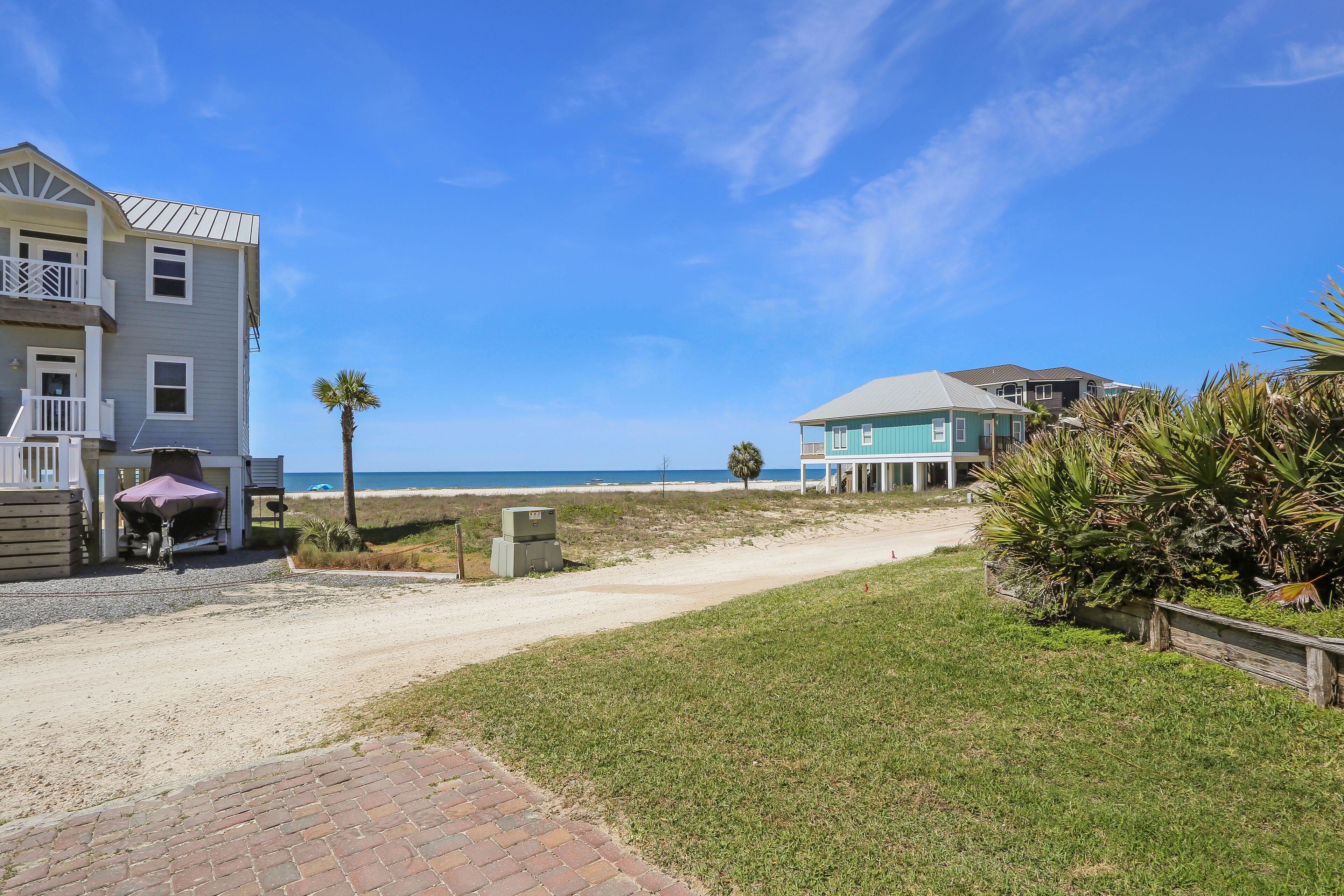 A beachfront property with a paved driveway, a covered barbecue area, and a view of the ocean.