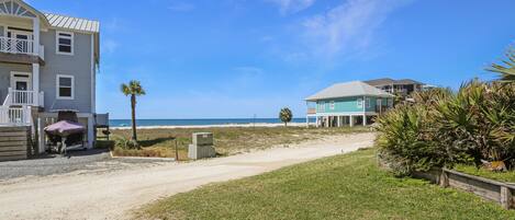 A beachfront property with a paved driveway, a covered barbecue area, and a view of the ocean.